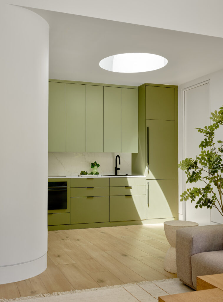 Bright, open ADU living space with oak accents, green cabinetry, and circular skylight in Lafayette, California.